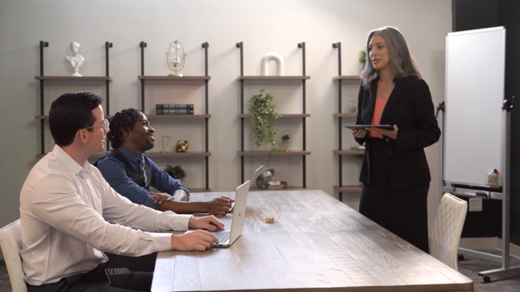 Woman leads meeting, speaking to two attentive colleagues at a table